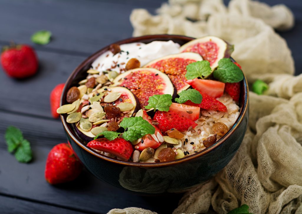 Delicious and healthy oatmeal with figs, seeds, strawberry and yogurt. Healthy breakfast. Fitness food. Proper nutrition.
