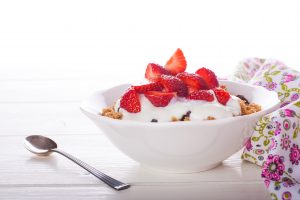 Yogurt with homemade granola or muesli and fresh strawberries for healthy morning breakfast, selective focus, over white. Healthy food background with copy space for text.