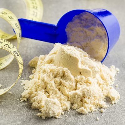 Whey protein powder in scoop and measuring tape.