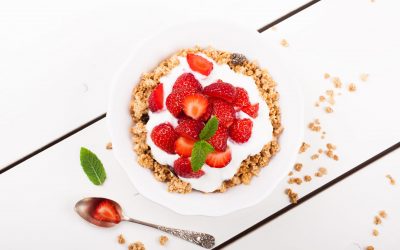 Yogurt with homemade granola or muesli and fresh strawberries for healthy morning breakfast, selective focus, over white. Healthy food background. Top view.
